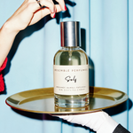 A hand reaching for Self extrait de parfum by Resemble Perfumes on a gold tray